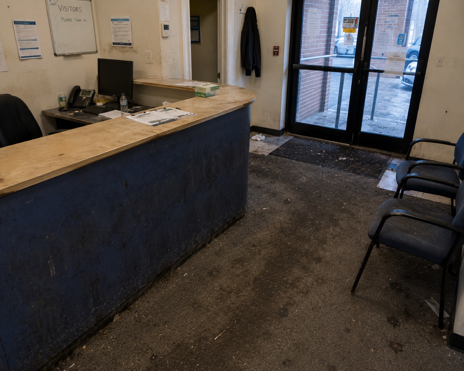Reception area before cleaning, with a grubby counter, marked walls and a heavily soiled entrance floor