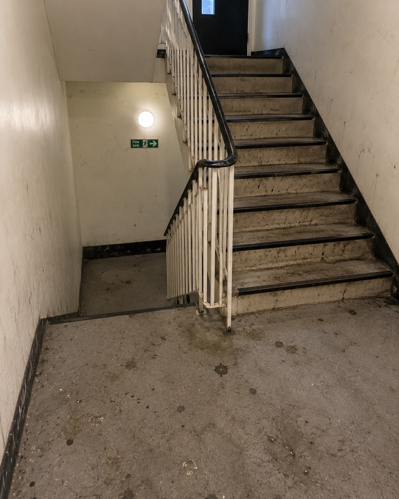 Communal stairwell before cleaning, with ingrained dirt on every tread and marked walls
